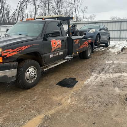 D's Towing black wrecker towing an SUV on a winter job site