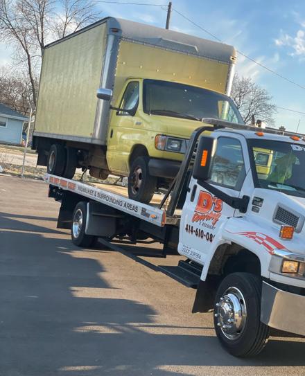 Yellow box truck loaded on a D's Towing flatbed