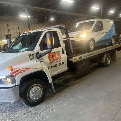 Cargo van loaded on the D's Towing flatbed inside the shop