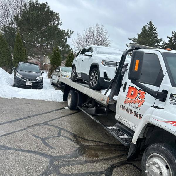 Snow-covered SUV loaded on a D's Towing flatbed during a Wisconsin winter call